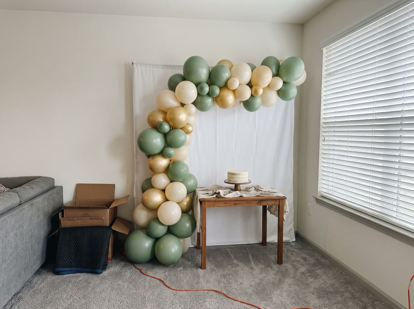 Half balloon arch swooping over a cake table in a condo