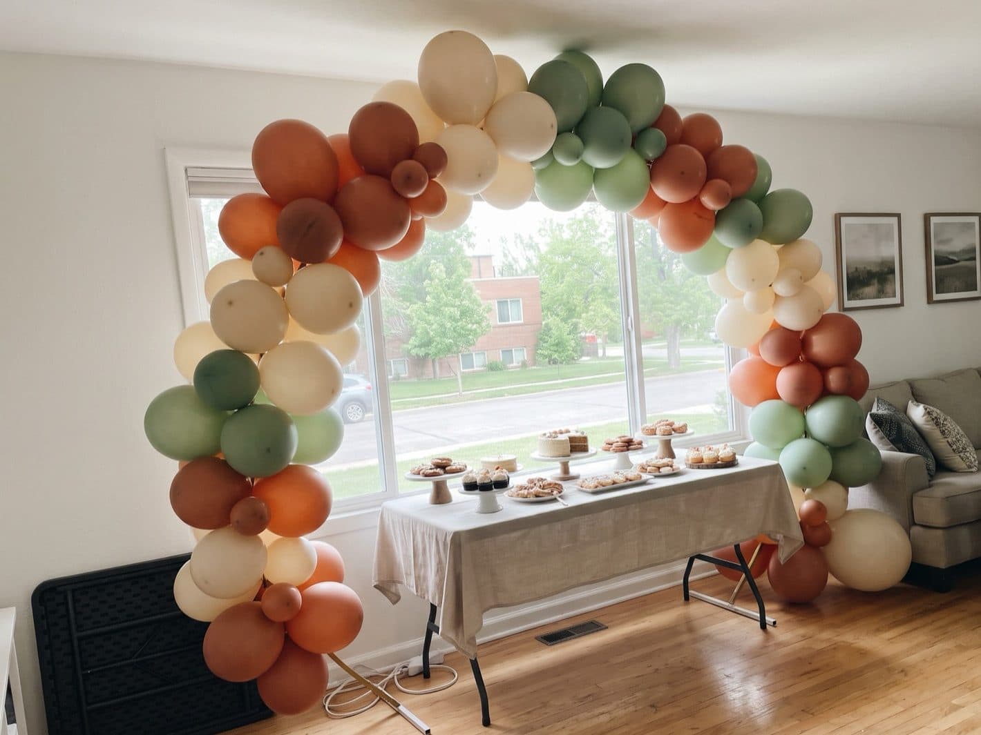 Organic balloon arch in terracotta, cream and sage over a dessert table at a Denver birthday party